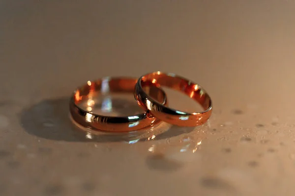 Anillos de boda se encuentran en la superficie con gotas de agua — Foto de Stock