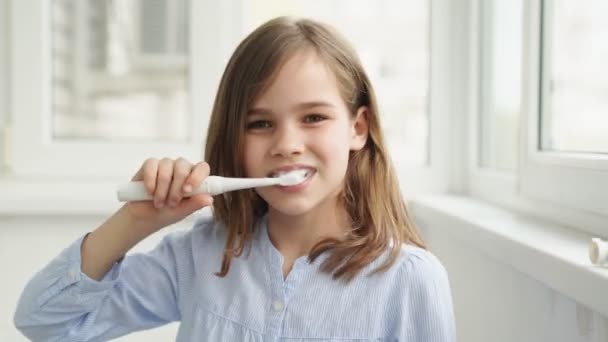 Divertida adolescente chica limpia dientes cepillo de dientes eléctrico — Vídeos de Stock