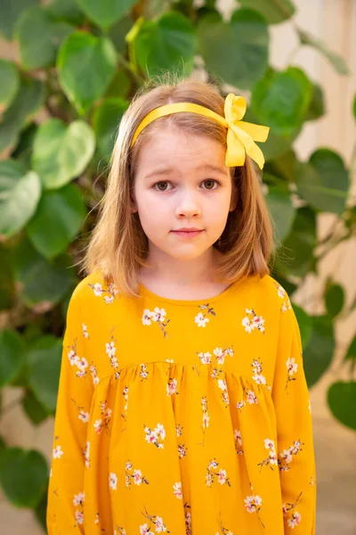 Surprised little girl,yellow dress.ribbon in hair — Stock Photo, Image