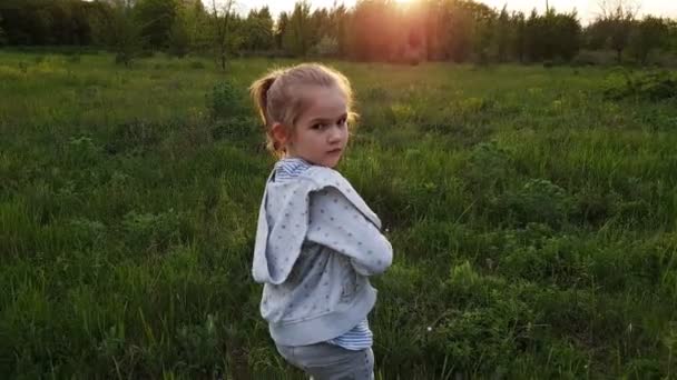 Klein meisje is op het veld, draait zich om en begint te rennen. — Stockvideo