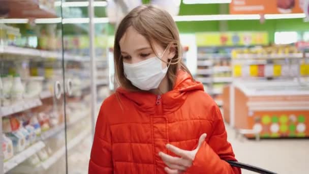 Chica en máscara médica recoge productos lácteos en la tienda — Vídeos de Stock