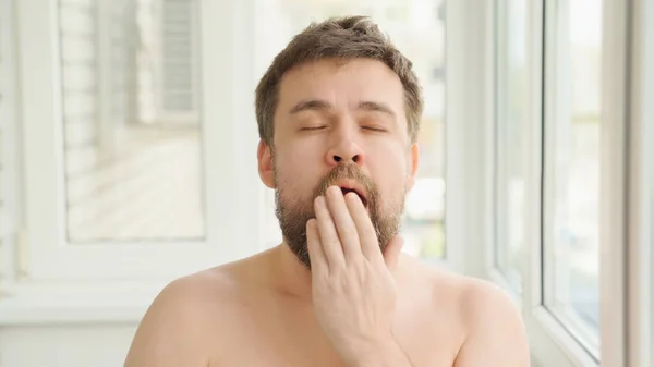 Сонний чоловік чистить зуби електричною зубною щіткою — стокове фото