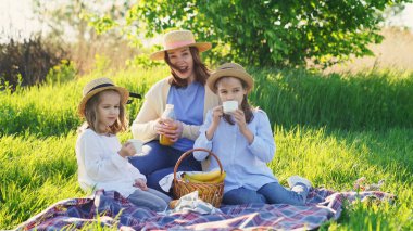 Çimenlikteki piknikte şapkalı bir anne..