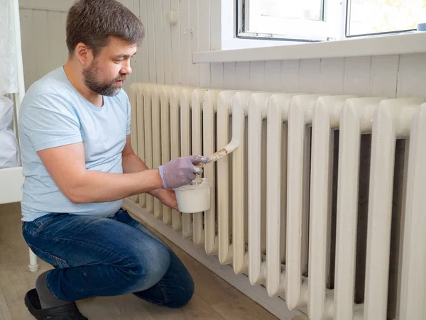 Mann mit Handschuhen streicht Heizkörper in Wohnung — Stockfoto