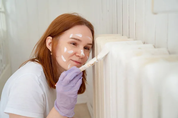 Mujer en guante pintura calefacción radiador — Foto de Stock