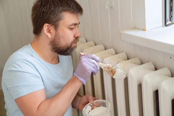 Mann mit Handschuhen streicht Heizkörper in Wohnung — Stockfoto