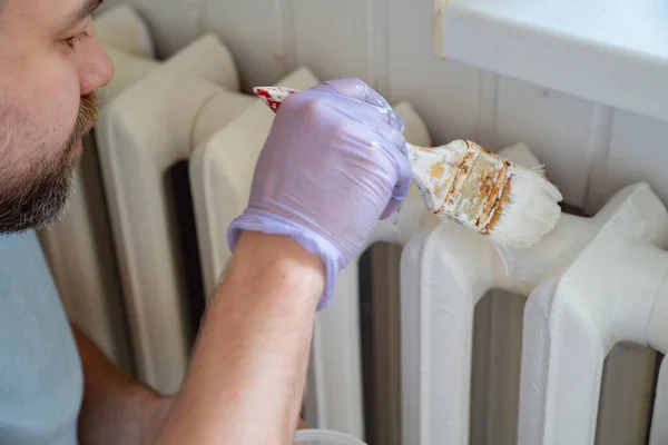 Mann mit Handschuhen streicht Heizkörper in Wohnung — Stockfoto