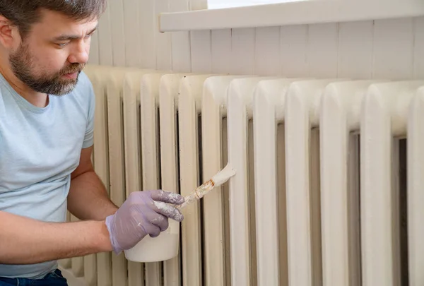 Человек в перчатке покраска радиатор отопления в доме — стоковое фото
