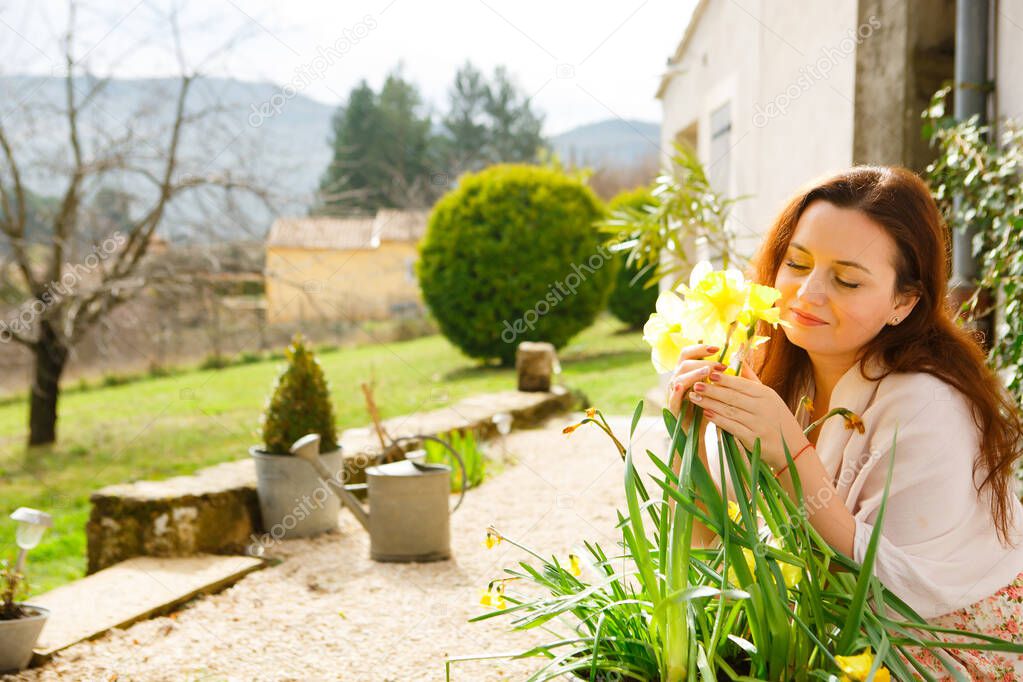 Girl cares for flowers in garden in country house
