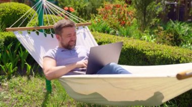Mutlu adam hamakta yatar ve bilgisayarla çalışır..