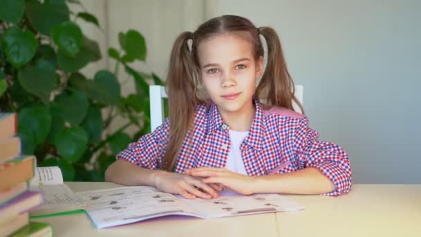 Teenager-Schulmädchen im karierten Hemd bei den Hausaufgaben. zeigt O 'k Zeichen. — Stockvideo