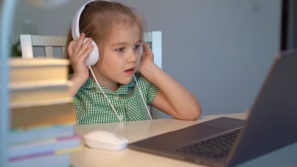 Gyerek lány fülhallgató hallgat zenét vagy leckét, távolság online tanulás otthon — Stock videók