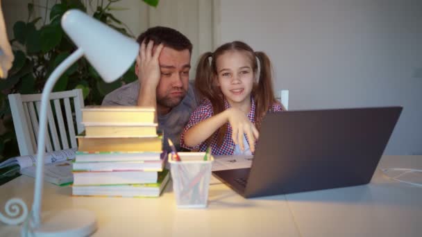 Сонный папа помогает дочери делать забавные онлайн уроки на ноутбуке. дистанционное обучение — стоковое видео