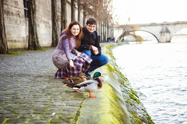 Pareja de amantes en el río Sena en París alimentan patos. viajar en primavera en Europa . — Foto de Stock