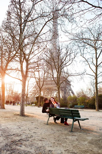 Los amantes se sientan en un banco cerca de la torre Eiffel en París. viajar en primavera en Francia . — Foto de Stock