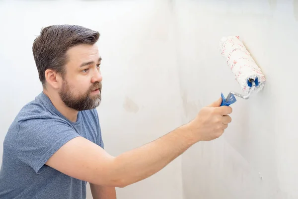 Mann bemalt Wandrolle mit weißer Farbe. — Stockfoto
