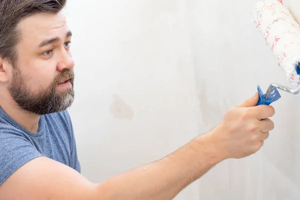 Mann bemalt Wandrolle mit weißer Farbe. — Stockfoto