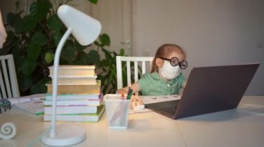 Gözlüklü ve maskeli kız laptopta öğreniyor. uzaklık eğitimi.