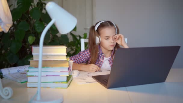 Schläfrige, müde Schulmädchen mit Kopfhörern hören Hörbuch oder Unterricht. — Stockvideo