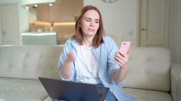 Połączenie wideo przez telefon. kobieta na kanapie z komputerem. — Wideo stockowe