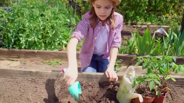 戴帽子的年轻漂亮的女孩和一个耙一起工作。一个年轻的农民. — 图库视频影像