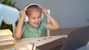 Kulaklık takan kız müzik dinliyor ya da ders alıyor, uzaktan internet üzerinden öğreniyor.