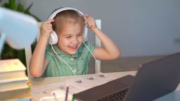 ヘッドフォンの子供の女の子は音楽やレッスンを聞きます,距離オンライン学習の家 — ストック動画