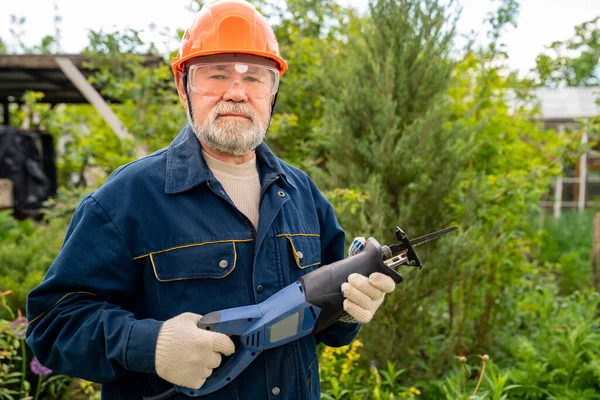 Älterer Mann mit Vollbart und Brille mit Säbelsäge. — Stockfoto