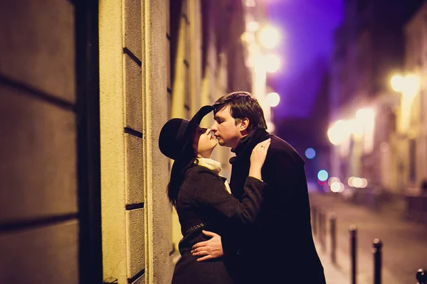 모자쓴 여자와 키스하고 파리의 밤 거리를 걷는 남자. — 스톡 사진