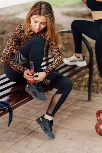 Dívka sportovec ve sportovním oblečení nosí závaží na nohy. fitness trénink venku. — Stock fotografie