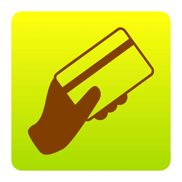 Ruka držící kreditní karty. Vektor. Hnědý ikona na zeleno žlutá přechodu čtverec se zaoblenými rohy na bílém pozadí. Izolovaný. — Stockový vektor