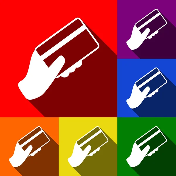 Mano con tarjeta de crédito. Vector. Conjunto de iconos con sombras planas en fondo rojo, naranja, amarillo, verde, azul y violeta . — Vector de stock