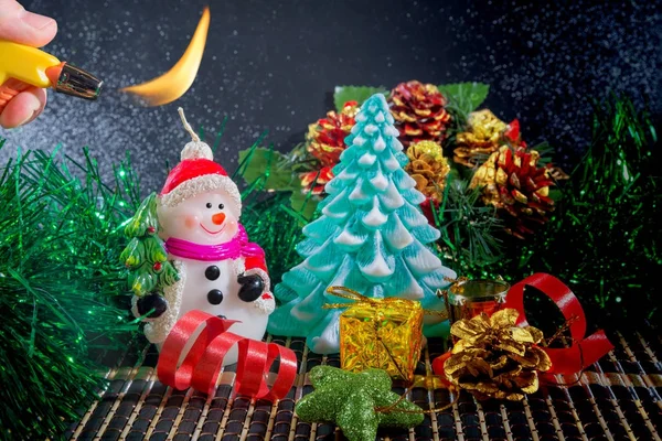 Kardan adam ve Noel ağacı Noel arka plan. Yeni yıl süslemeleri şeritler ve koniler oyuncaklarla. Kardan adam mum kırmızı bir şapka ve yüzümde bir gülümseme.