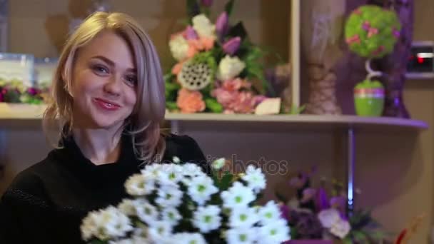 Mulher hispânica jovem trabalhando como florista na loja de flores e olhando para a câmera, sorrindo com buquê na mesa — Vídeo de Stock