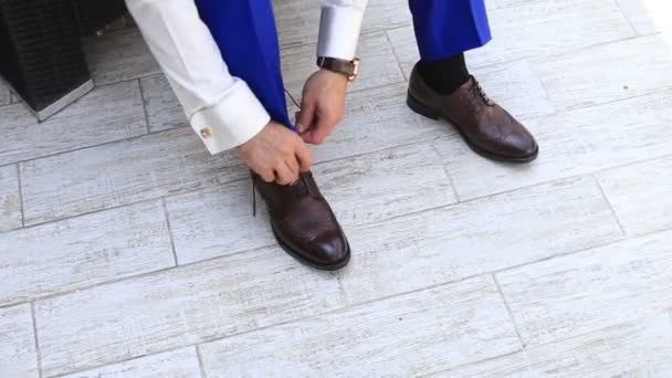 Hombre caucásico con pantalones de traje que atan cordones de zapatos en sus zapatos de cuero brillante marrón — Vídeos de Stock