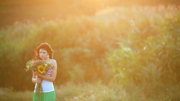 Tânăra fată stând cu grijă în iarbă în natură. Fata miroase a câmp de flori şi visează. Portretul unei tinere, frumoase fete. Emoții de bucurie, jenă. Fetele se confruntă cu aproape . — Videoclip de stoc