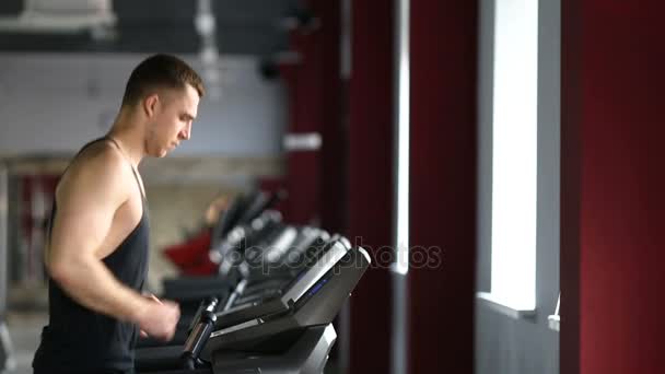 Young athletic men and women exercising and running on treadmill in sport gym. — Stock Video