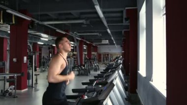 İnsanlar spor salonunda koşu bandında koşuyor.