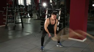 Kaslı adam kıvrım halatlar ile dalgalar yapıyor