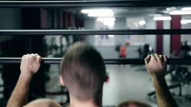 Fitness salonunda yavaş yatay çubuğu yukarı çekerek atletik erkek