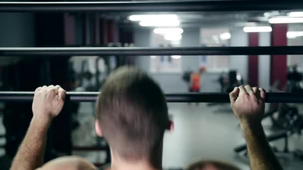 Sportlicher Mann zieht in Fitnessstudio langsam am Reck hoch — Stockvideo
