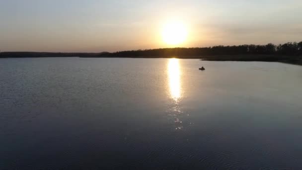 Imágenes de 4k Drone del pescador conduciendo en su barco en un lago al atardecer . — Vídeo de stock