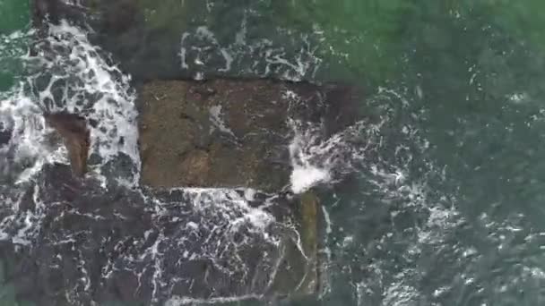 Aérea de las olas del océano lavándose sobre una roca de basalto negro — Vídeos de Stock