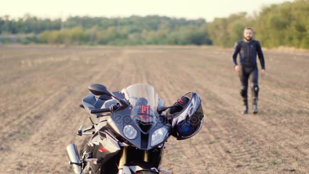 El hombre toma un casco de moto y sonríe — Vídeo de stock