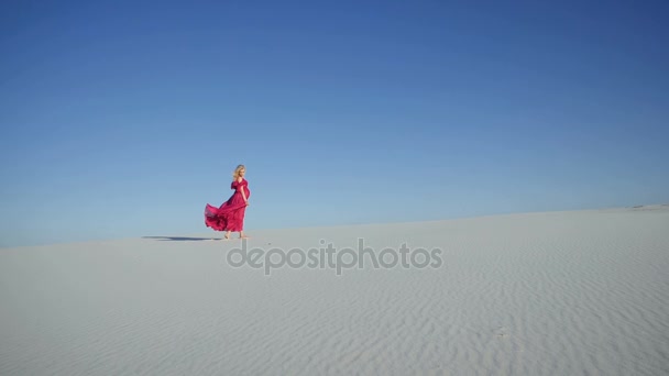 Chica rubia caminando en el viento hacia la cámara en una duna — Vídeos de Stock