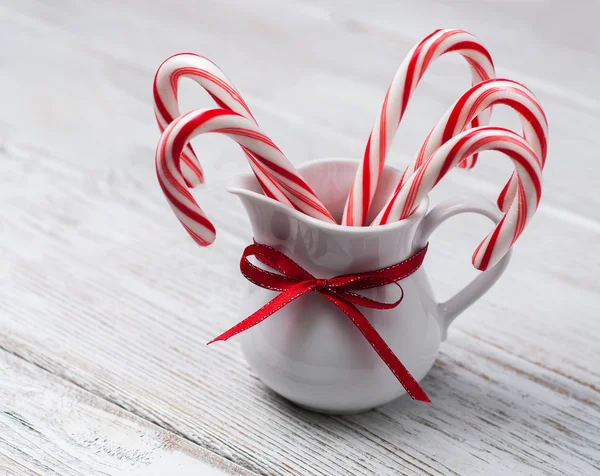 Jug with christmas candy canes on a wooden table — Stock Photo, Image