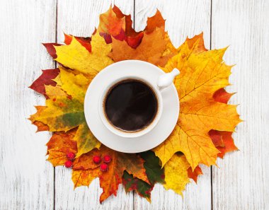 Bir fincan kahve ve sonbahar yaprakları.