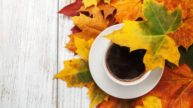 Bir fincan kahve ve sonbahar yaprakları.