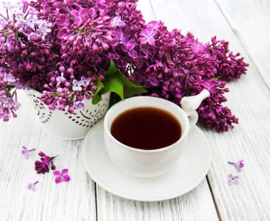Fincan çay ve eflatun çiçekler