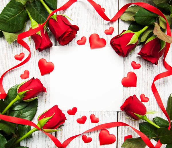 Rosas vermelhas e cartão de saudação — Fotografia de Stock